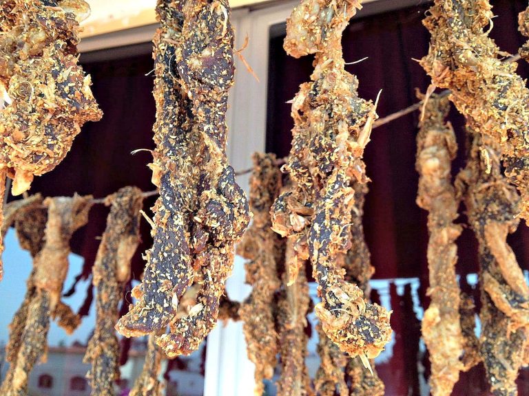 A photo of cured strips of meat hanging to dry on a line in order to make gueddid, a type of Moroccan dried meat.