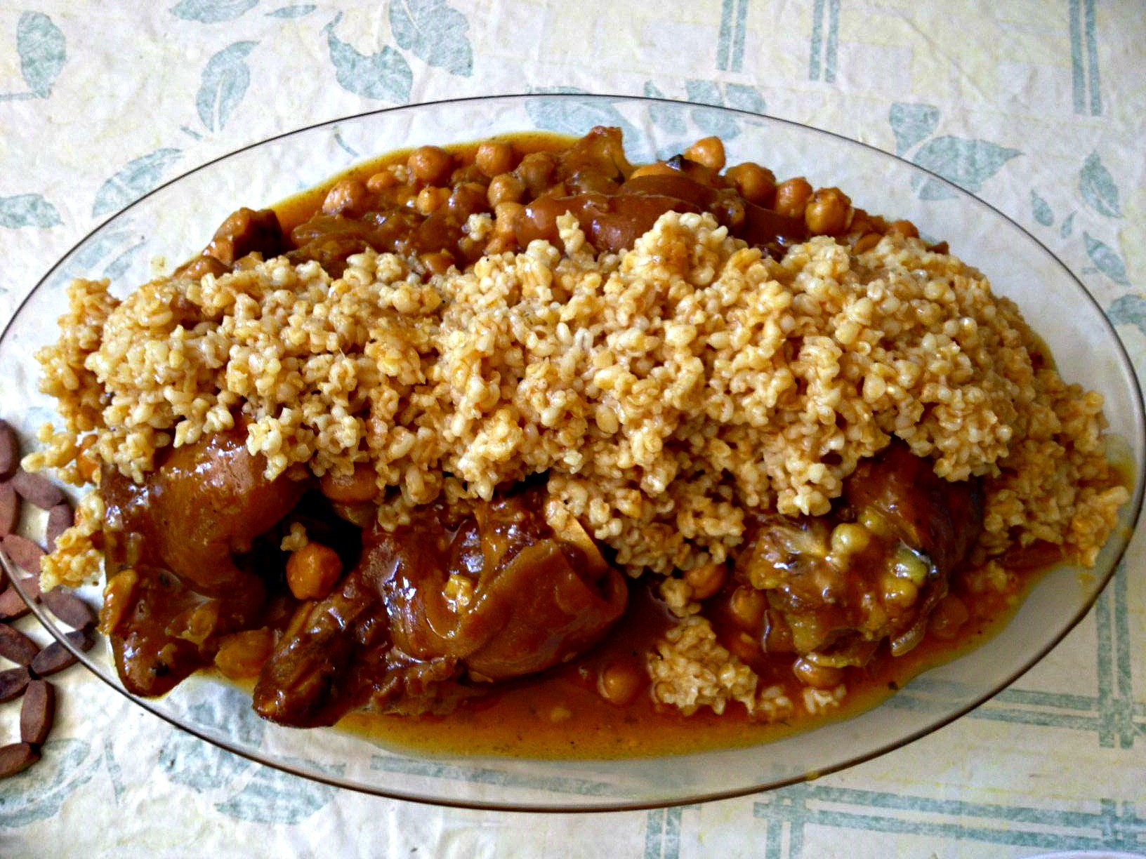 overhead image of a platter of Moroccan trotters and chickpeas topped by a garnish of wheat berries