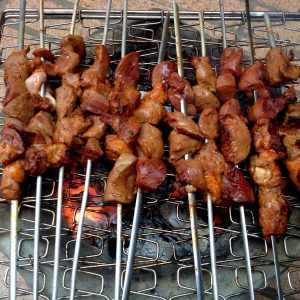 liver, heart and kidney brochettes cooking over charcoal