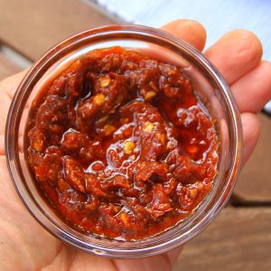 A bowl of harissa paste with dried red chili peppers
