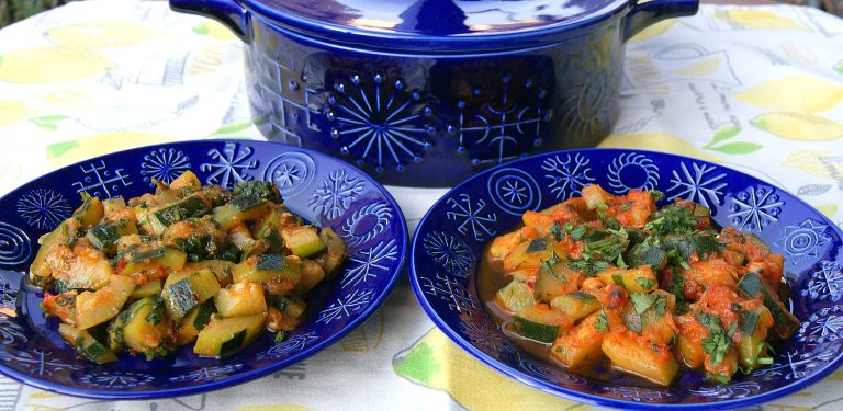 Two variations of chopped, cooked zucchini smothered with herbs and spices are shown side-by-side on decorated blue dishes.