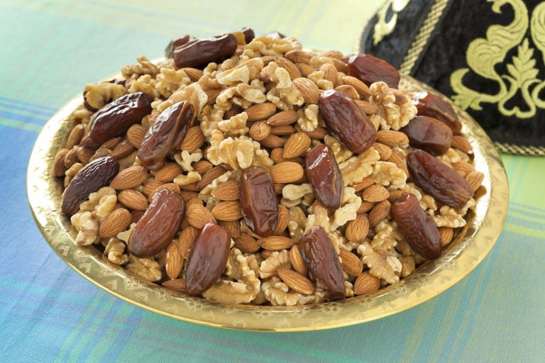 Walnuts, almonds and dates are mounded into a Moroccan serving dish. This assortment is a traditional food item to serve on Ashura.