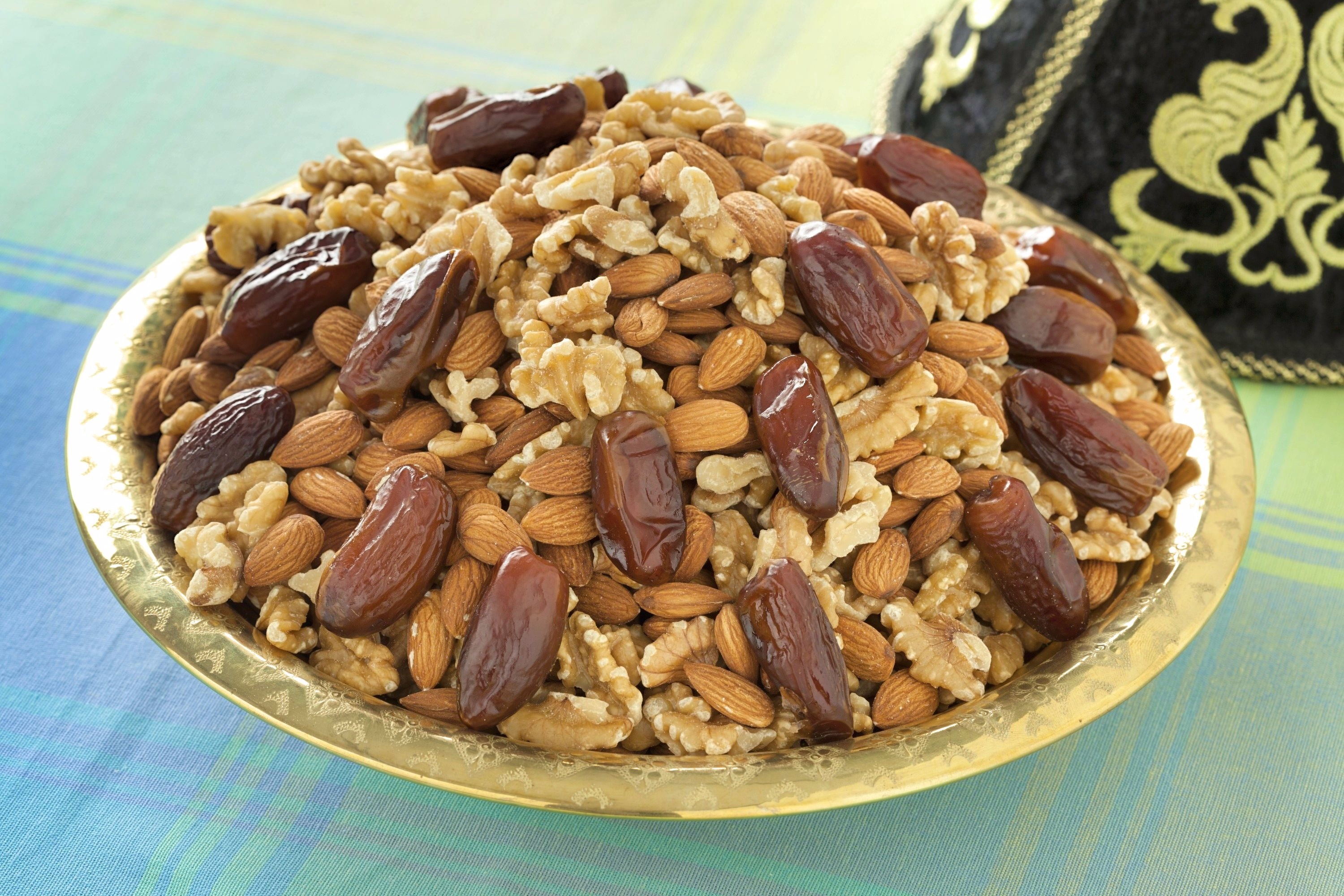 Walnuts, almonds and dates are mounded into a Moroccan serving dish. This assortment is a traditional food item to serve on Ashura.