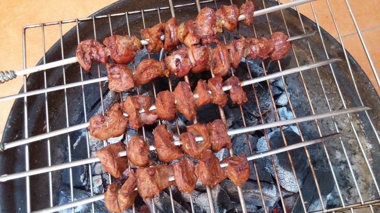 Skewers of heart and kidney cubes on the grill. The offal is almost cooked at this point.