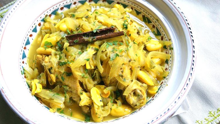 A platter of yellow-hued chicken topped with lots of tender onions and thin sauce. The dish is one of many in Moroccan cuisine that fall under the category of Qadra.