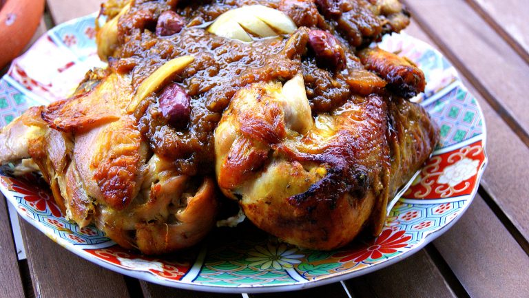 Moroccan chicken cooked m'qualli style and finished in the oven as m'hammar, topped with a thick onion sauce and decorated with preserved lemons and olives
