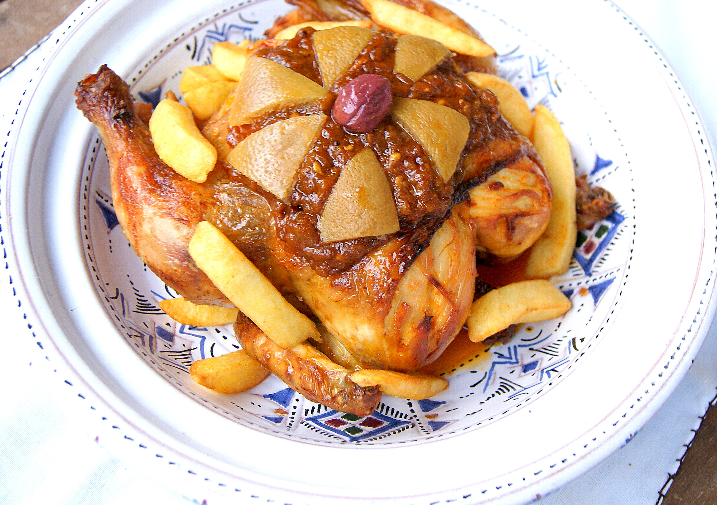 Moroccan chicken m'hammar topped with onion sauce, preserved lemons, purple olive and fried potatoes