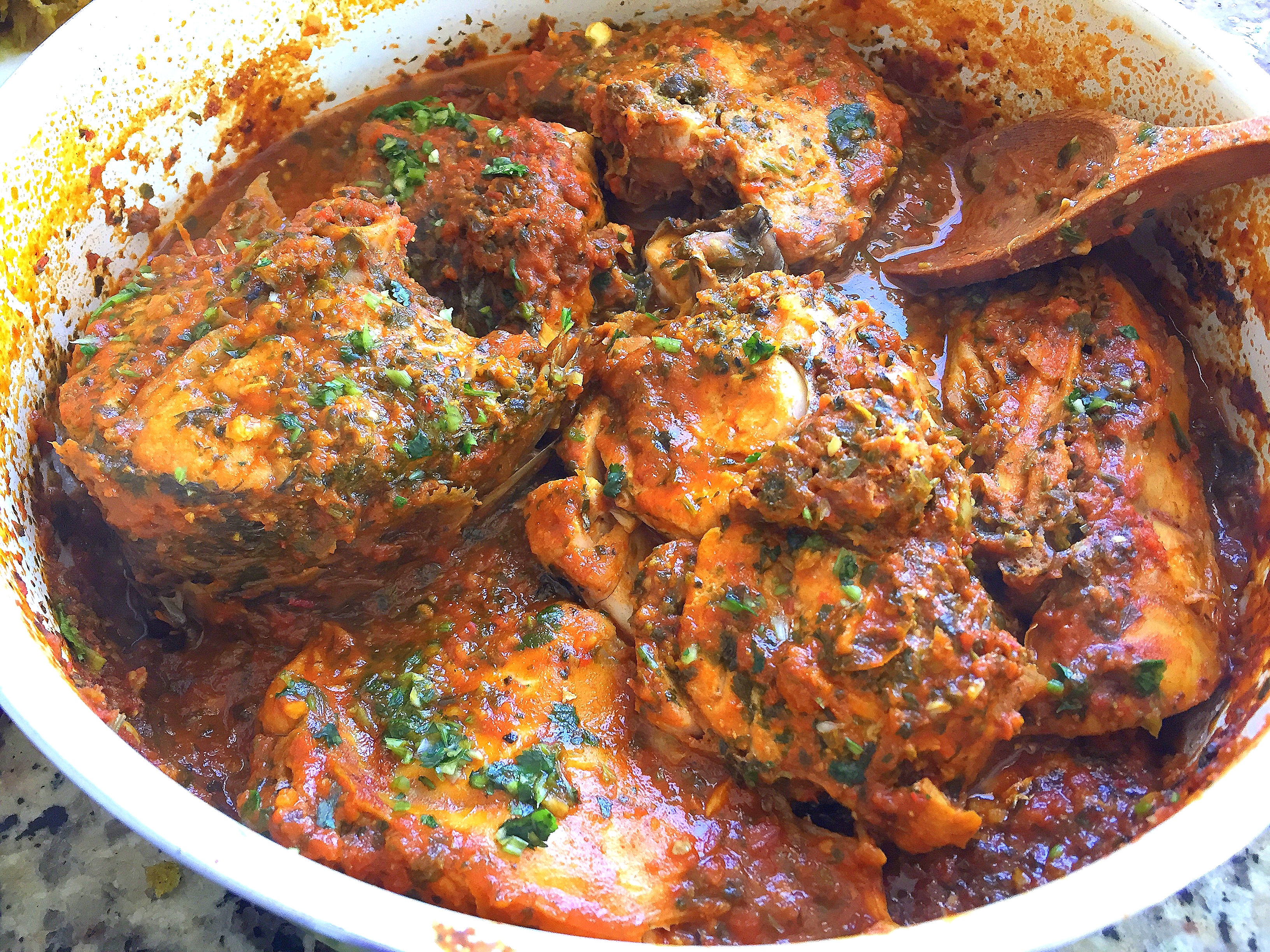 Cooked fish is shown in a skillet, covered in a Moroccan tomato- and chermoula-based sauce.