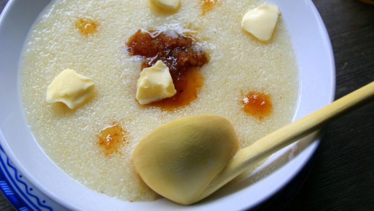 A deep plate filled with assida, a moroccan semolina porridge, dotted with butter and thick dark honey