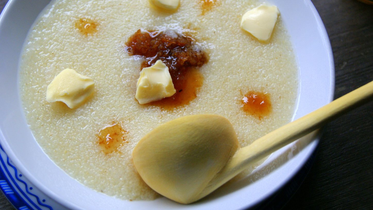 A deep plate filled with assida, a moroccan semolina porridge, dotted with butter and thick dark honey