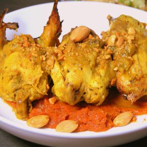 Moroccan chicken m'qualli on a bed of of pumpkin paste, garnished with crushed and whole almonds