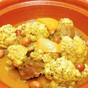 A Moroccan dish of beef and cauliflower with preserved lemon and olives in the base of a tagine.