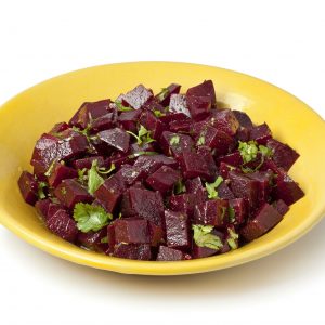 A small yellow bowl of Moroccan beet salad. The salad is made of diced, cooked beets which have been tossed with a vinaigrette and garnished with parsley.