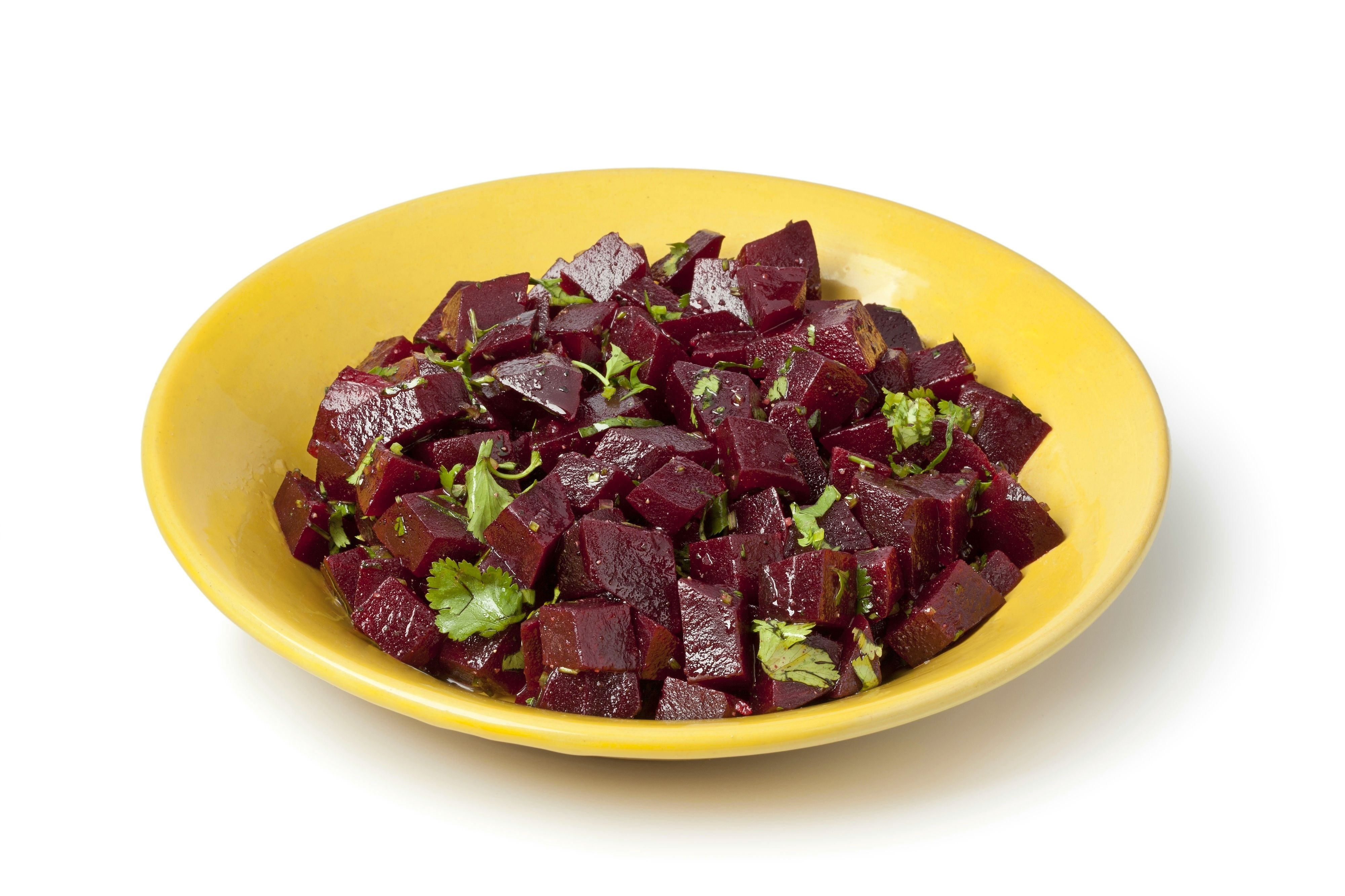 A small yellow bowl of Moroccan beet salad. The salad is made of diced, cooked beets which have been tossed with a vinaigrette and garnished with parsley.